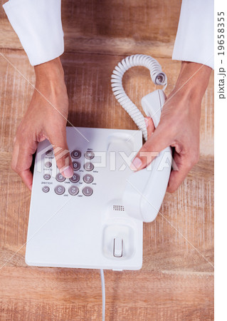 Businesswoman holding a phone at her desk Businesswoman holding a phone at her desk 19658355