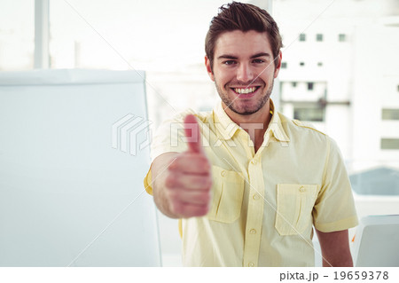 Smiling creative businessman by his desk 19659378