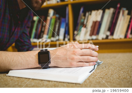 Student studying on floor in library wearing smart watch 19659400