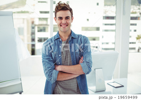 Smiling creative businessman by his desk 19659499