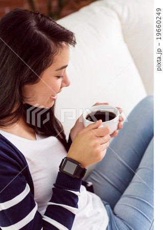 Asian woman relaxing on couch with coffee 19660249