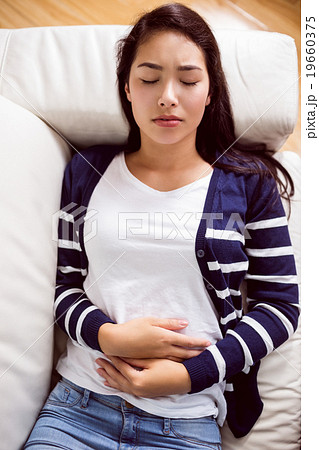 Asian woman lying on the couch with cramps 19660375