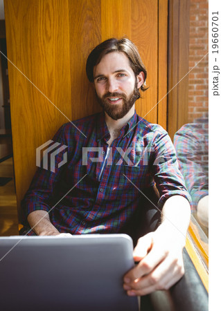 Hipster student using laptop in canteen 19660701