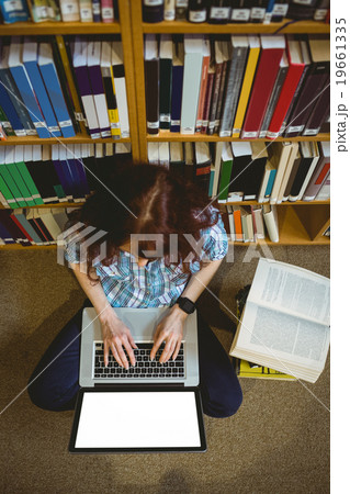 Mature student in library using laptop Mature student in library using laptop 19661335