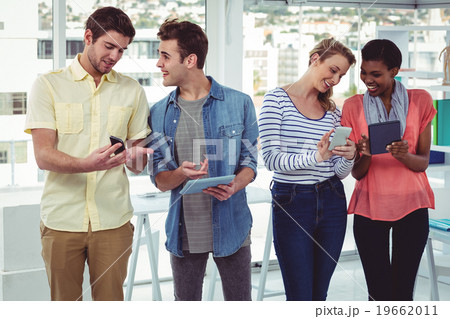 Smiling creative team standing in a line using technology 19662011