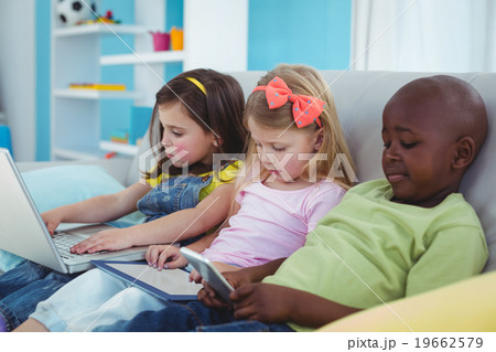 Happy kids sitting together with a tablet and laptop and phone 19662579