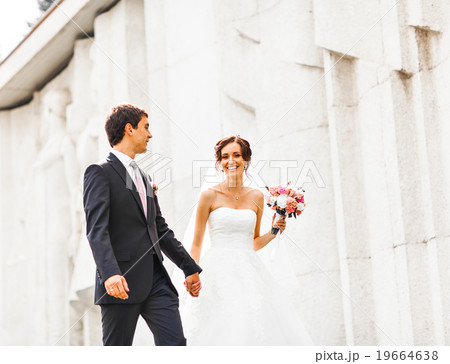 Young wedding couple walking together at park Young wedding couple walking together at park 19664638