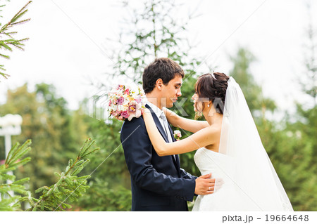 Young wedding couple walking together at park Young wedding couple walking together at park 19664648