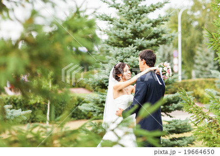 Young wedding couple walking together at park Young wedding couple walking together at park 19664650