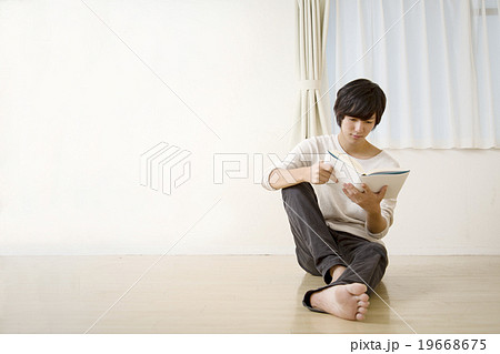 床に座り読書をする若い男性の写真素材