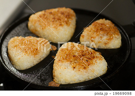 おうちで焼きおにぎり 南部鉄器の焼きおにぎり器を使いキッチンのガスコンロでこんがりと焼くシーン おうちで焼きおにぎり 南部鉄器の焼きおにぎり器を使いキッチンのガスコンロでこんがりと焼くシーン 19669098