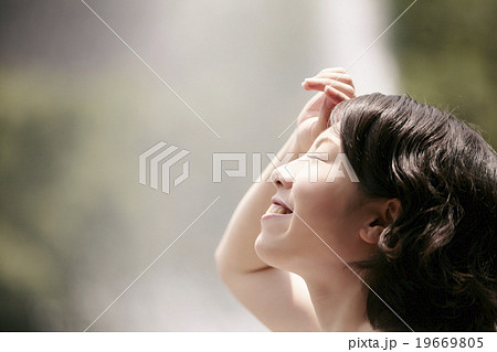 目を閉じて上を見上げる女性の横顔の写真素材