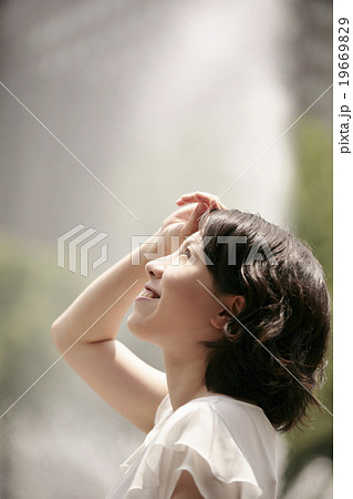 眩しそうに上を見上げる女性の横顔の写真素材
