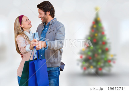 Composite image of smiling couple showing credit card and shoppi Composite image of smiling couple showing credit card and shoppi 19672714