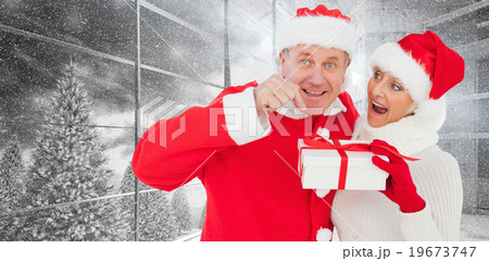 Composite image of festive mature couple holding gift Composite image of festive mature couple holding gift 19673747