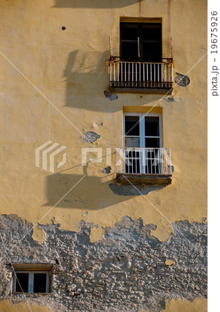 Old Italian yellow stone house front with balcony 19675926