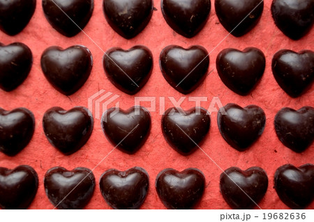 並べたハート型チョコレート 赤背景の写真素材