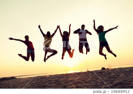 smiling friends dancing and jumping on beach 19688952