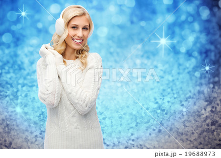 smiling young woman in winter earmuffs and sweater 19688973