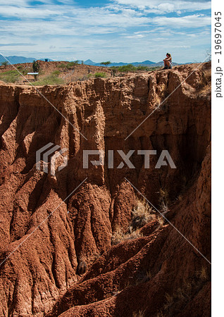 Blond young woman sitting on cliff of red 19697045
