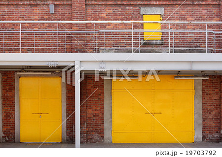 Metal yellow factory door on brick wall 19703792