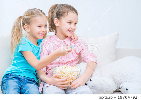 Cheerful little sisters sitting on the sofa Cheerful little sisters sitting on the sofa 19704792