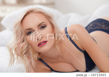 Attractive young woman is luxuriating in bedroom 19715005