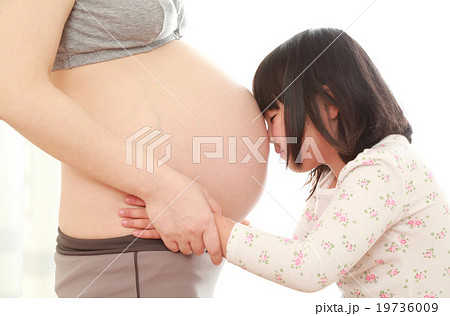 妊婦さんのお腹に顔をつける子供の写真素材