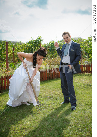 Bride and groom digs the soil in the garden Bride and groom digs the soil in the garden 19737363