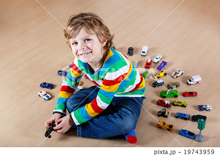 Little blond child playing with lots of toy cars 19743959