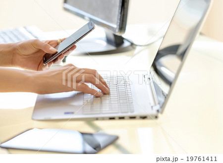 Business woman texting and typing on laptop keyboard 19761411