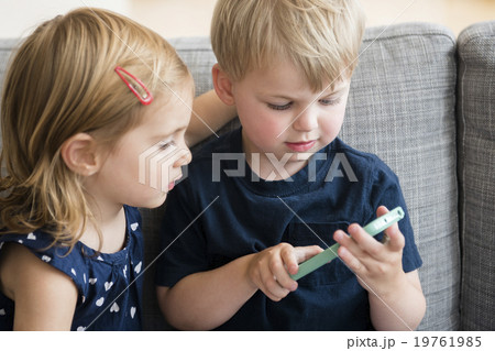 Brother with sister (2-3) playing with smart phone 19761985