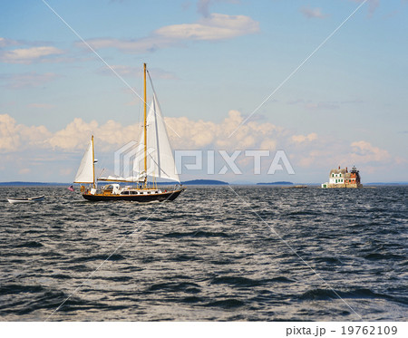 Sailboat in sea and Rockland Harbor Breakwater Lighthouse in distance Sailboat in sea and Rockland Harbor Breakwater Lighthouse in distance 19762109