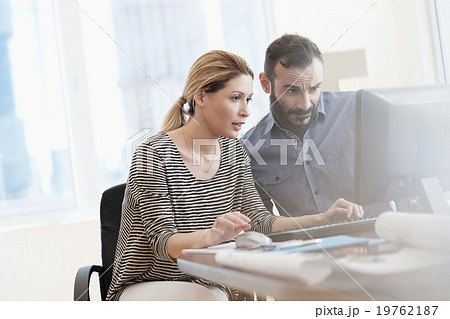 Man and woman looking at computer in office 19762187