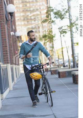 Man walking with bicycle in city 19762344