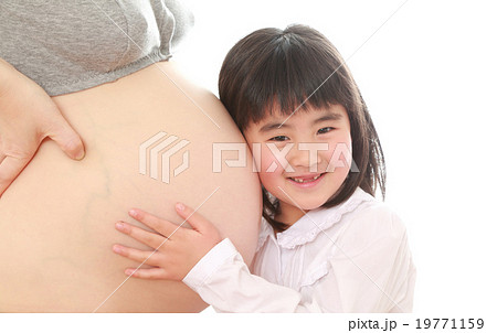 妊婦さんのお腹に顔をつける子供の写真素材