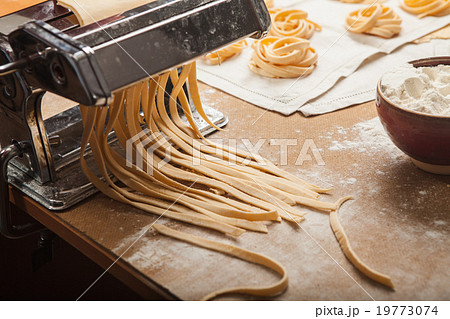 The fresh pasta and  machine on kitchen table 19773074