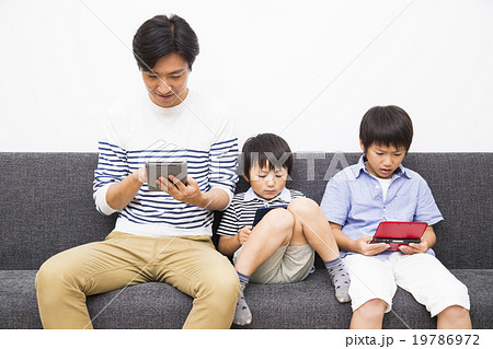 ゲームをするお父さんと息子2人の写真素材