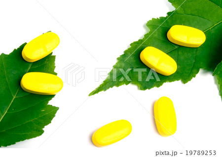 yellow vitamin pills over green leaves yellow vitamin pills over green leaves 19789253