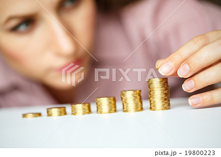 Woman stacking gold coins into increasing columns Woman stacking gold coins into increasing columns 19800223