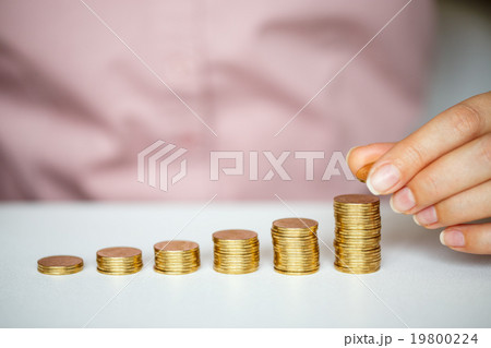 Female hand stacking gold coins into increasing columns Female hand stacking gold coins into increasing columns 19800224