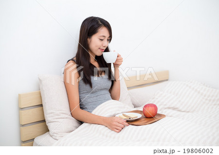 Woman having breakfast on bed Woman having breakfast on bed 19806002