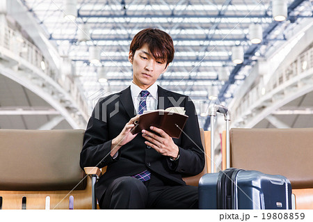 空港のロビーで手帳を見るビジネスマン 空港のロビーで手帳を見るビジネスマン 19808859
