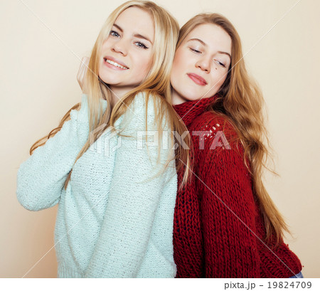 Two young girlfriends in winter sweaters indoors Two young girlfriends in winter sweaters indoors 19824709