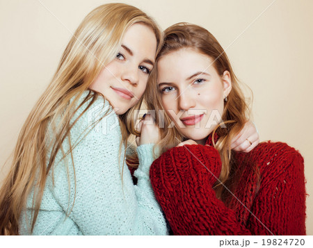 Two young girlfriends in winter sweaters indoors Two young girlfriends in winter sweaters indoors 19824720