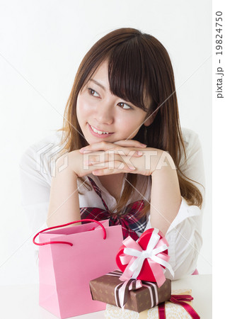 たくさんのプレゼントを前に頬杖をつく女子高校生 喜ぶプレゼント選びの写真素材