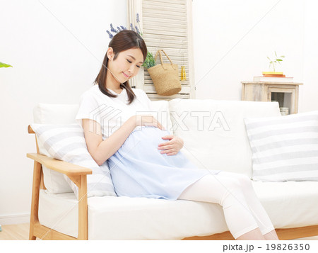 ソファーに座ってお腹を触る妊婦の写真素材 19826350 Pixta