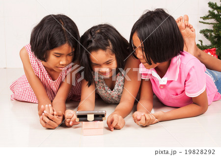 little asian girl watching movie on mobile phone in the room little asian girl watching movie on mobile phone in the room 19828292