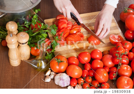Closeup of female hands slicing tomatoes 19830938