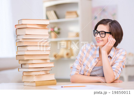 Young girl sitting in front near pile of books. Young girl sitting in front near pile of books. 19850011